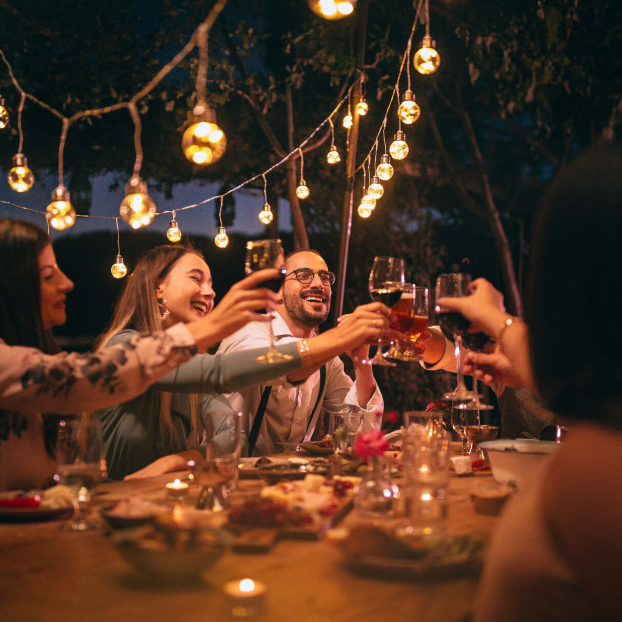 Friends toasting with wine and beer at rustic dinner party